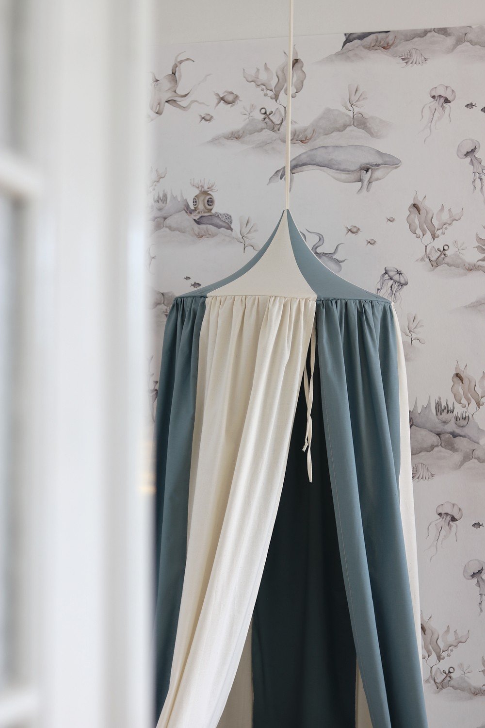 6. Close-up of blue and cream canopy with a pointed top against whimsical wallpaper
