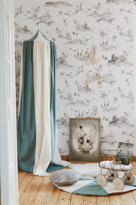 5. Blue and cream canopy in a nursery with whimsical wallpaper, wooden flooring, and decorative items