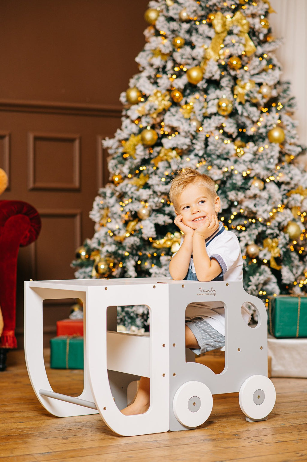 1. Child sitting at white Montessori learning table with Christmas tree in background