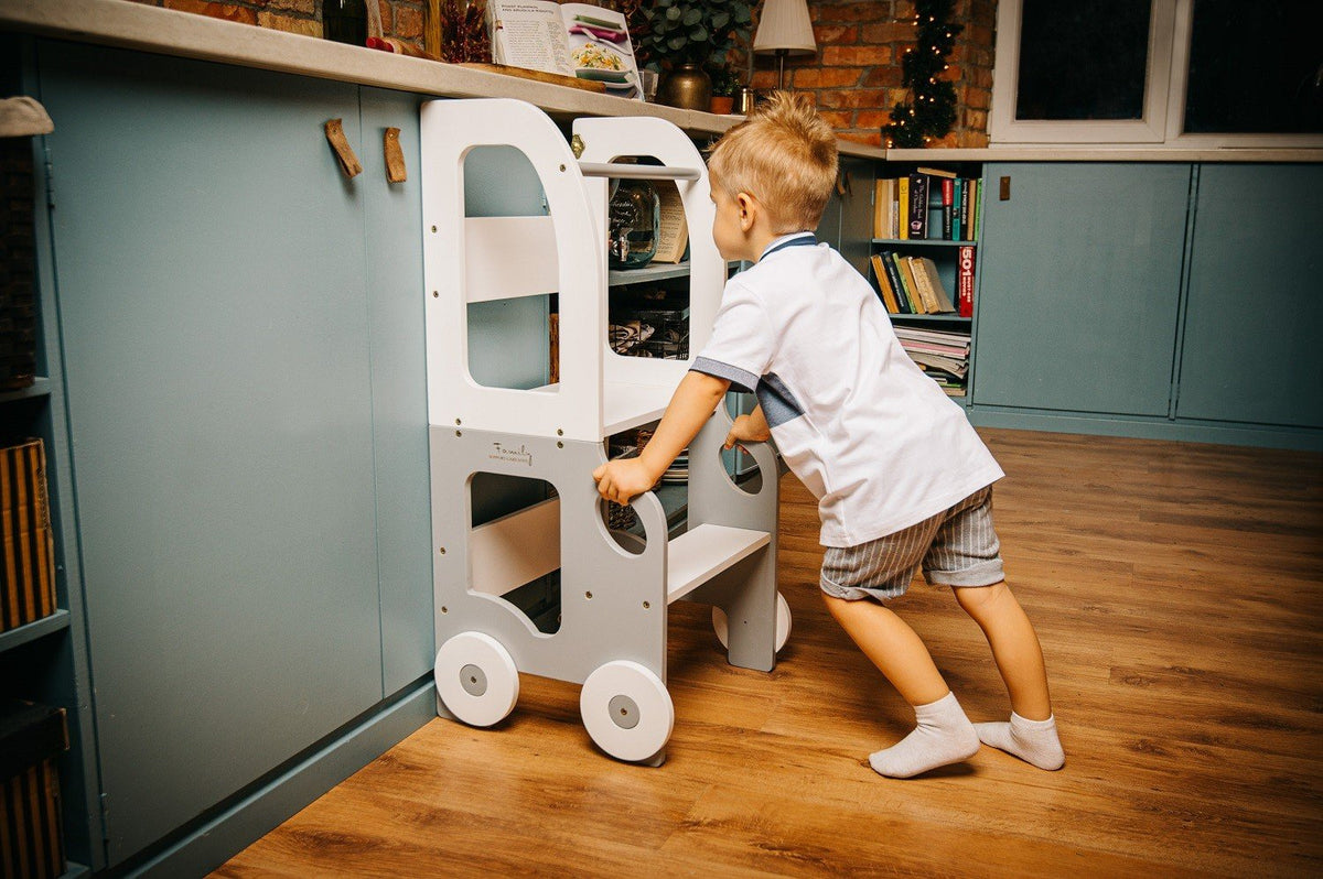 1. Child pushing grey and white Montessori kitchen step stool in kitchen