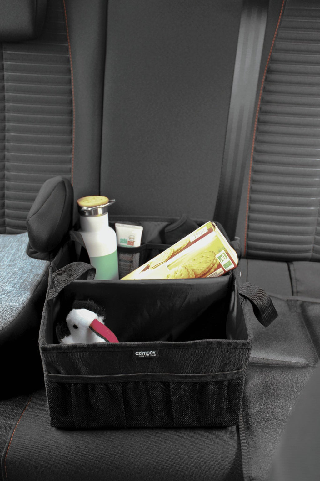2. Black Ezimoov car organizer bag on car seat with books, water bottle, and toy
