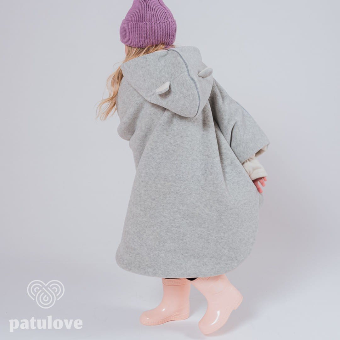 3. Back view of child wearing grey Patulove car poncho with bear ears, purple hat, and pink boots in studio setting