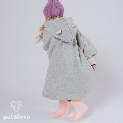 3. Back view of child wearing grey Patulove car poncho with bear ears, purple hat, and pink boots in studio setting