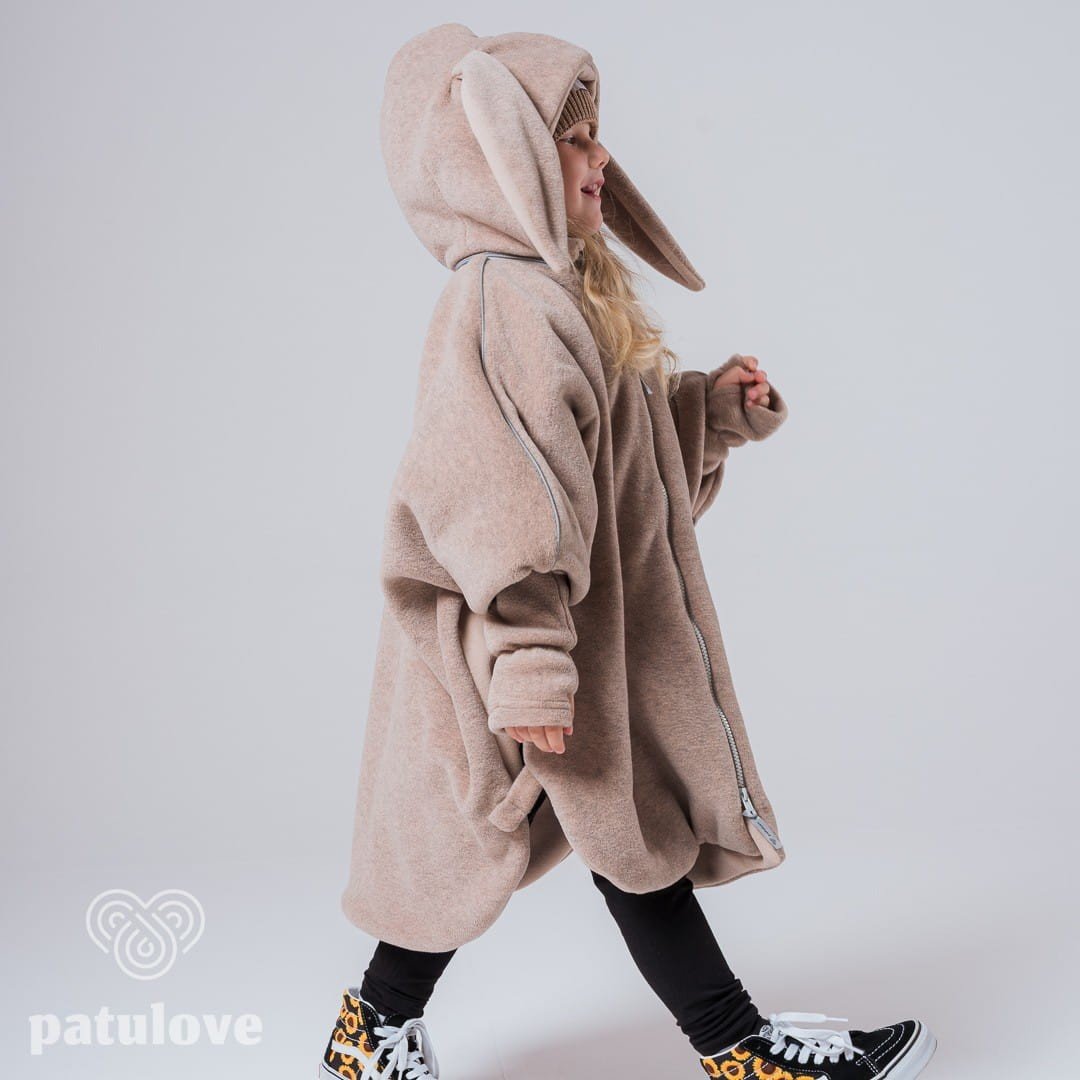 2. Side view of child in Patulove beige bunny car poncho with hood, walking in studio