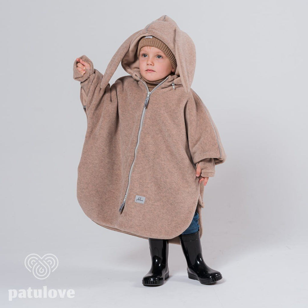 3. Child in Patulove beige bunny car poncho with hood, standing with arm raised in studio