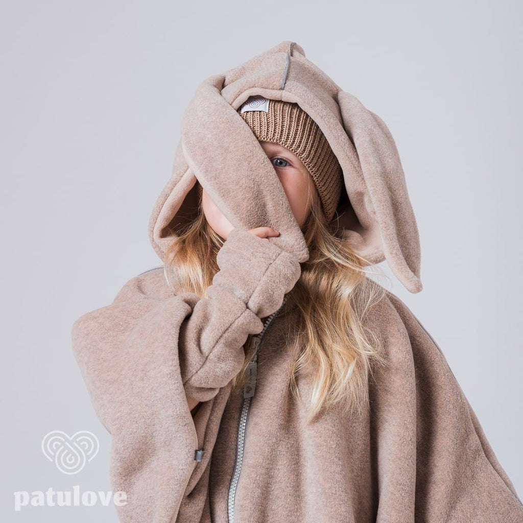 7. Close-up of child in Patulove beige bunny car poncho, playfully covering face with sleeve in studio