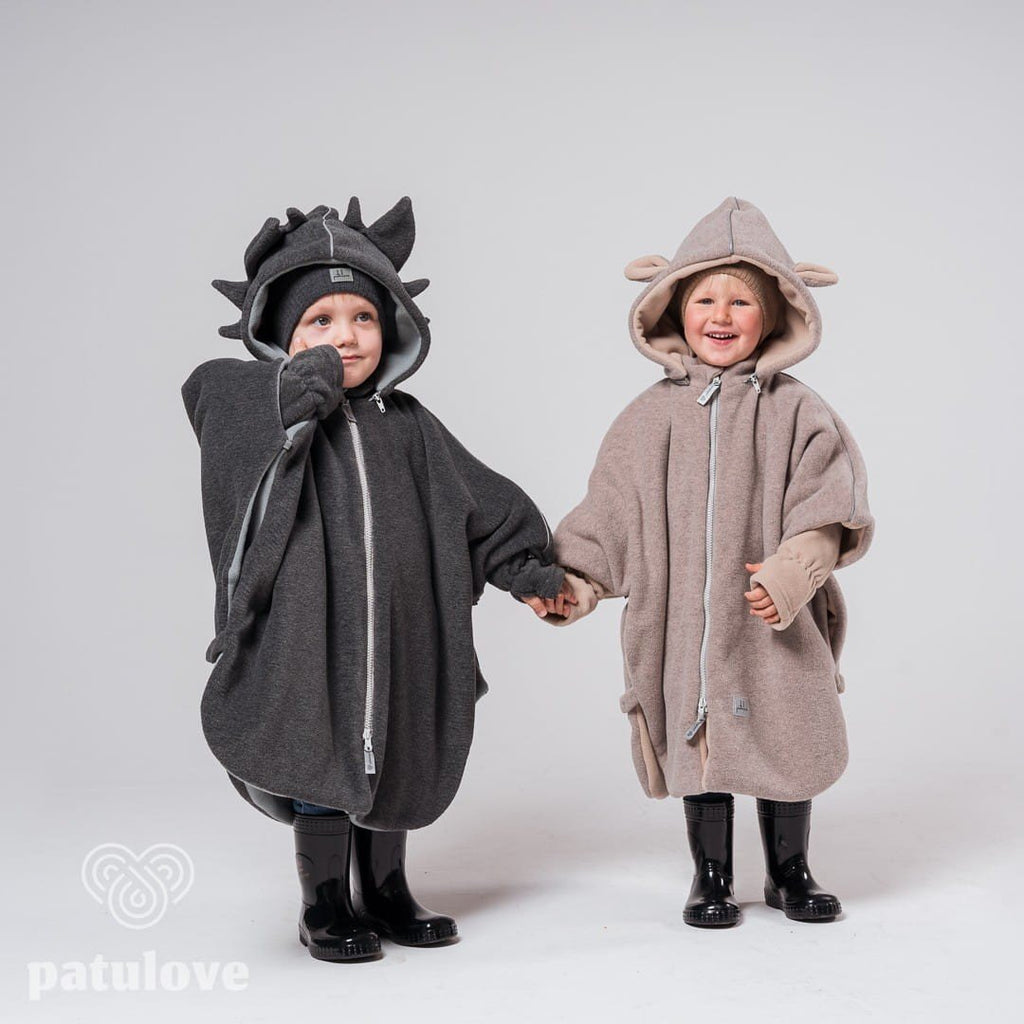 3. Two children wearing Patulove car ponchos, one dragon-themed and one bunny-themed, holding hands in studio setting
