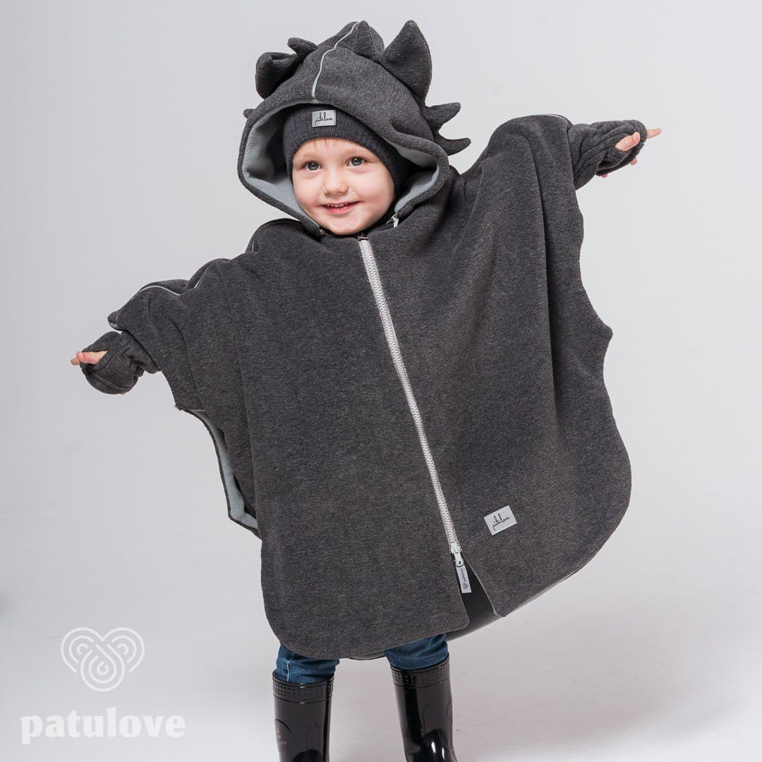 1. Child wearing Patulove dragon-themed car poncho with hood and spikes, standing with arms outstretched in studio setting