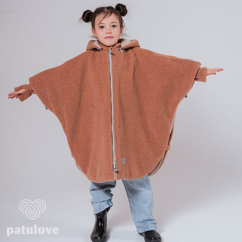 4. Girl in Patulove fox car poncho with arms outstretched, wearing jeans and black boots in studio