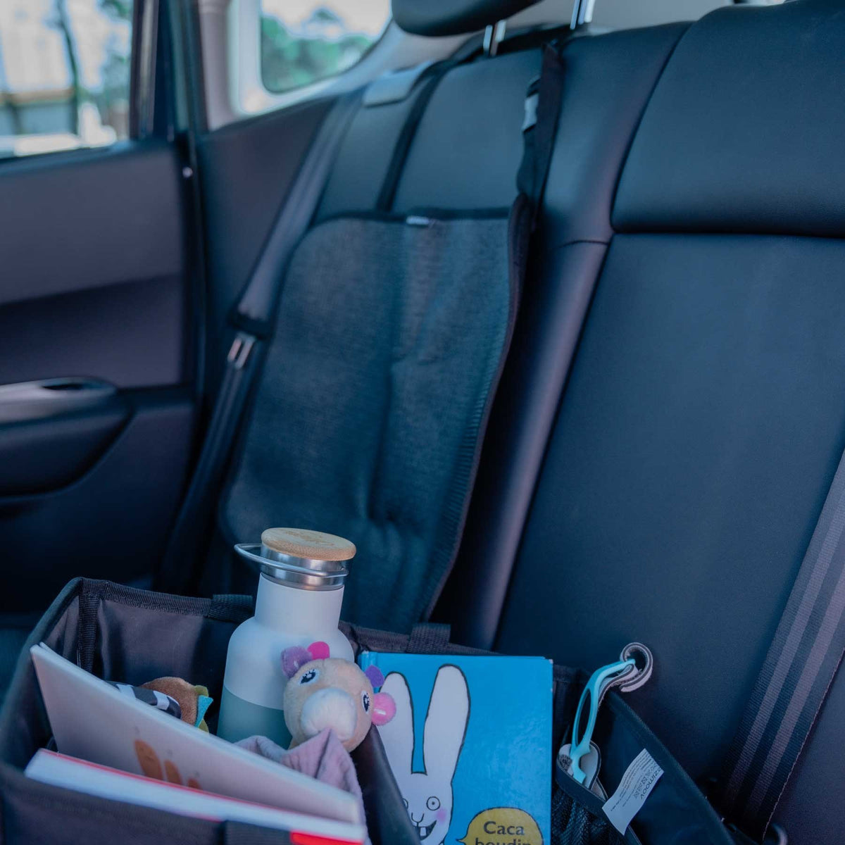 1. Black Ezimoov EZI MAT CLASSIC car seat cover in backseat of car with storage items