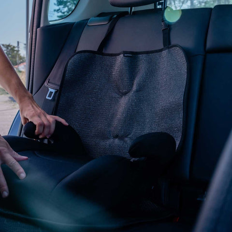 1. Person adjusting black Ezimoov EZI MAT CLASSIC car seat cover in backseat of car