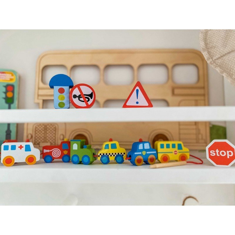 10. Wooden threading blocks with vehicles and road signs displayed on a shelf with a wooden bus backdrop