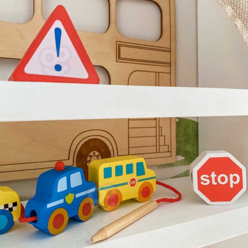 2. Close-up of wooden threading blocks featuring police car, school bus, and stop sign on a shelf