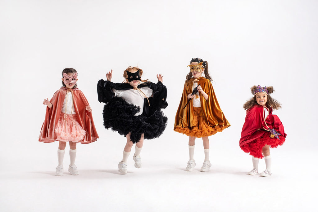 2. Four children in colorful costumes, one wearing a black cat mask, posing playfully in a studio