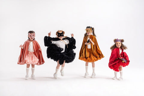 2. Four children in colorful costumes, one wearing a black cat mask, posing playfully in a studio