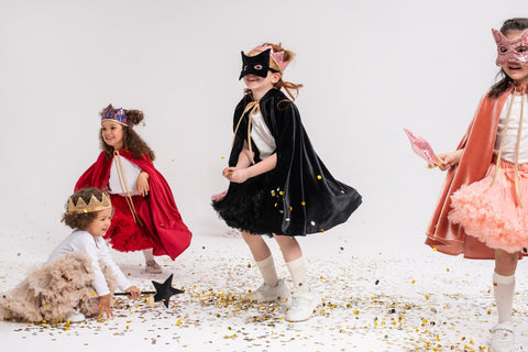4. Group of children in costumes, one wearing a black cat mask, playing with confetti