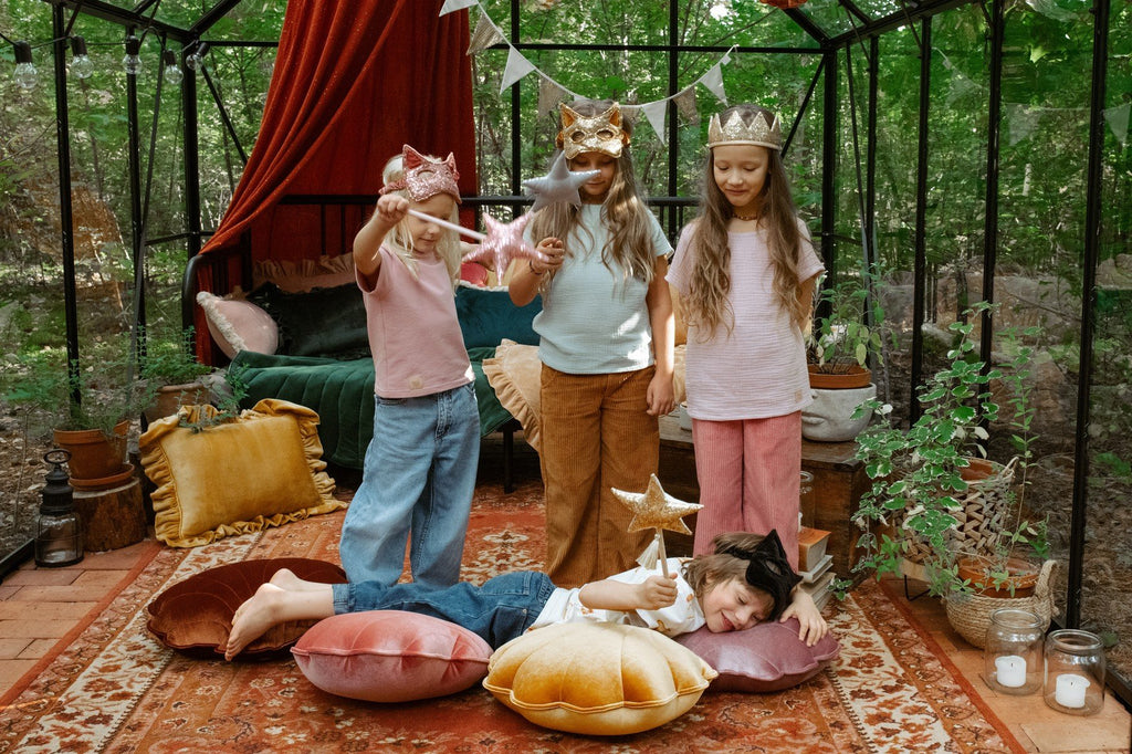 6. Four children in a decorated room, one wearing a black cat mask, playing with wands