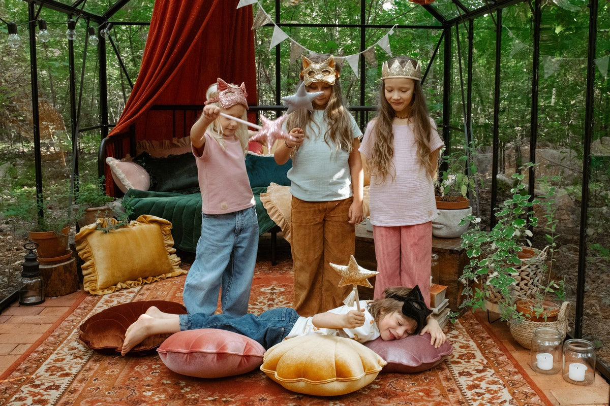 6. Four children in a decorated room, one wearing a black cat mask, playing with wands