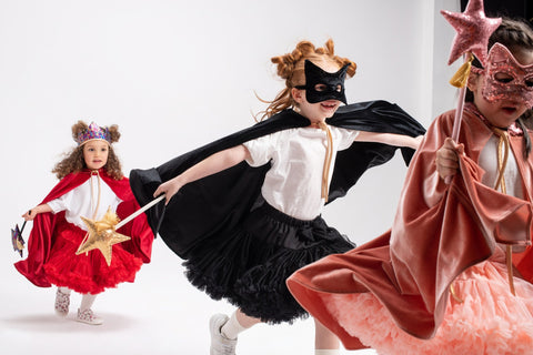 3. Children running in costumes, one with a black cat mask and cape, holding a wand