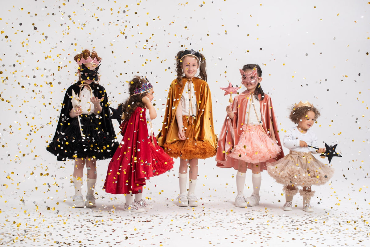 13. Five children in colorful costumes, one with a black cat mask, surrounded by confetti