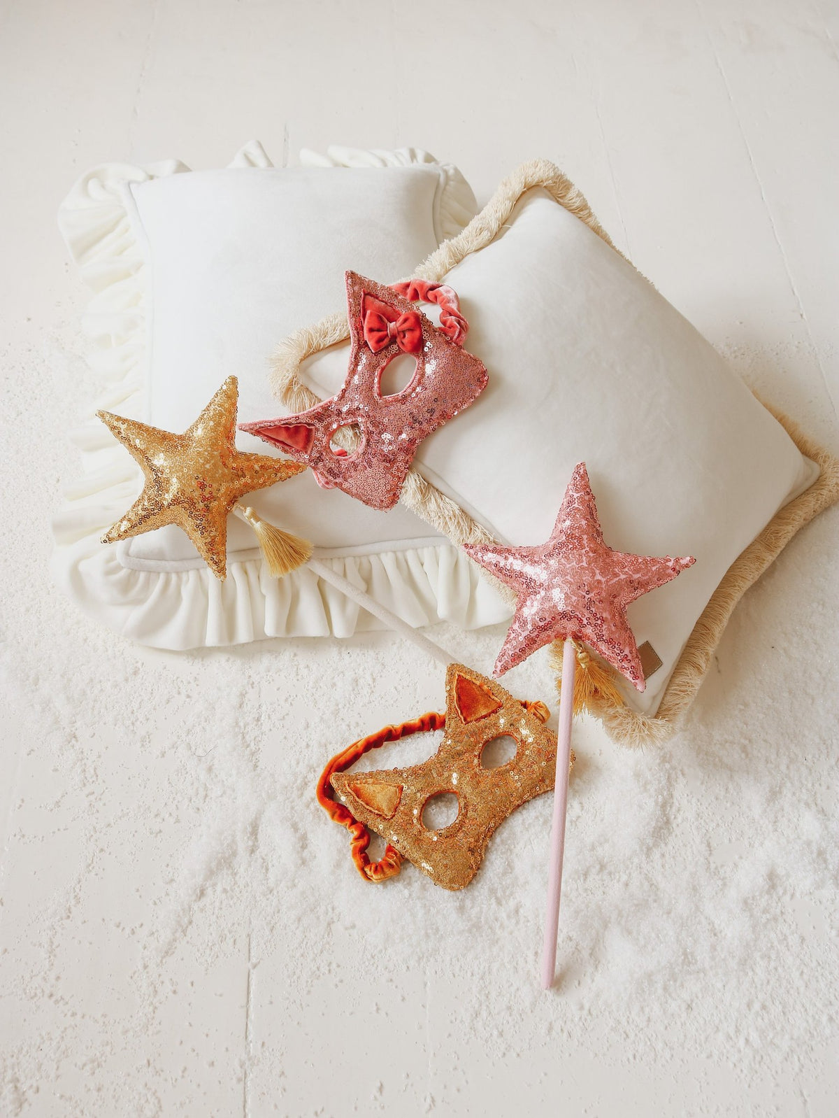 4. Flat lay of gold and pink sequin cat masks with star wands on white pillows