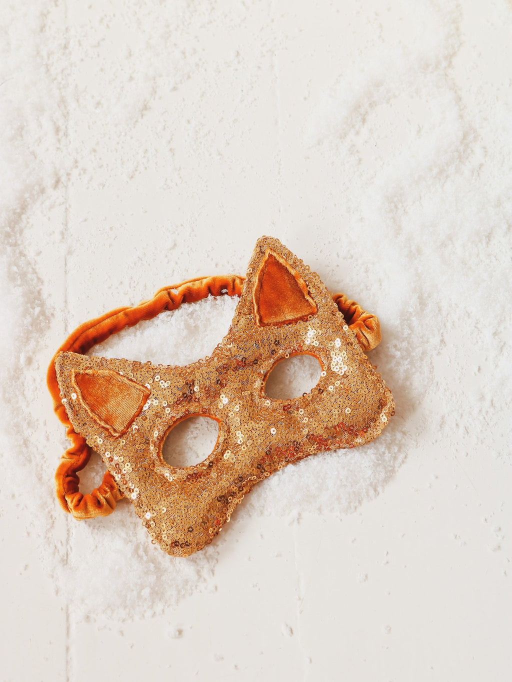 4. Flat lay of gold sequin cat mask with orange elastic band on white textured background