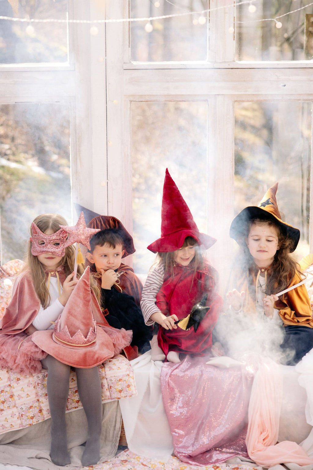 1. Four children in costume, one wearing pink sequin cat mask, sitting in a sunlit room
