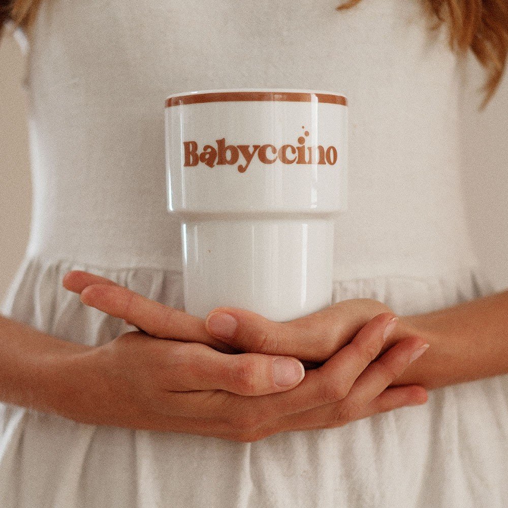 3. Close-up of Terra Mamma Babyccino ceramic mug held by woman in white dress, showing logo and design