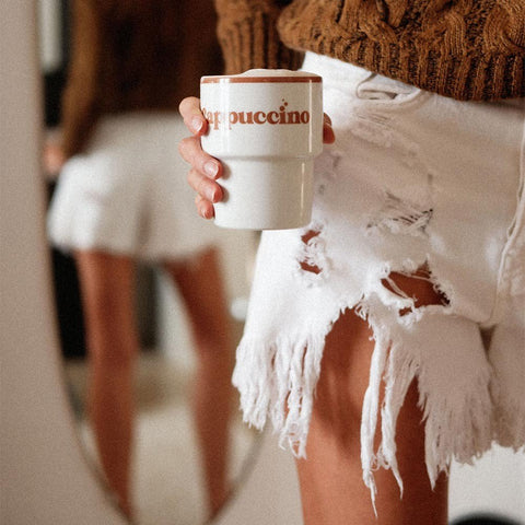 5. Person in brown sweater and white shorts holding Terra Mamma ceramic cappuccino mug