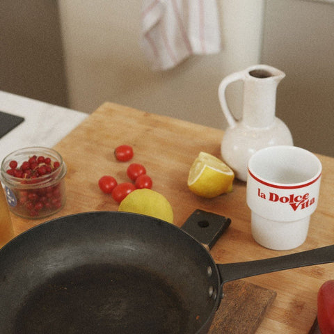 5. Terra Mamma 'La Dolce Vita' ceramic mug on kitchen counter with fruits, pan, and pitcher