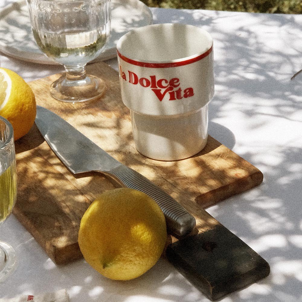 3. Terra Mamma 'La Dolce Vita' ceramic mug on outdoor table with lemons, knife, and glassware