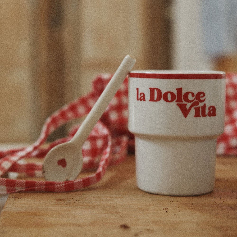 2. Terra Mamma 'La Dolce Vita' ceramic mug with red text on wooden table with red checkered cloth and spoon