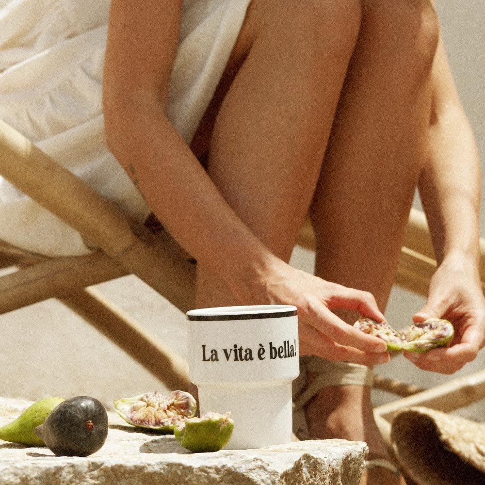 7. Close-up of Terra Mamma ceramic mug with 'La vita è bella!' text next to fresh figs outdoors