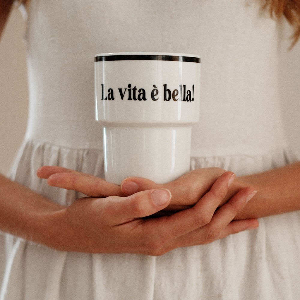 1. Woman in white dress holding Terra Mamma ceramic mug with 'La vita è bella!' text
