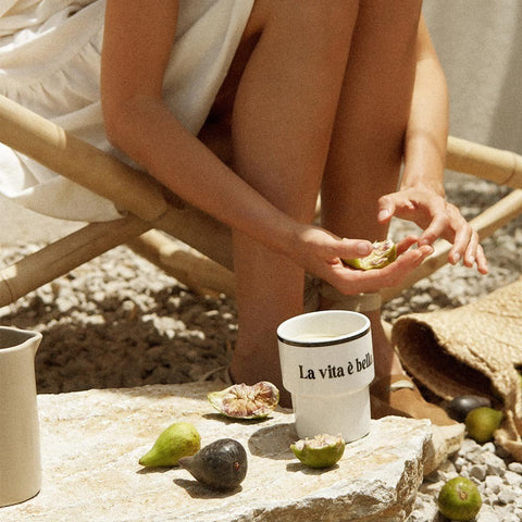 4. Woman seated outdoors with Terra Mamma ceramic mug and fresh figs, embodying Italian lifestyle