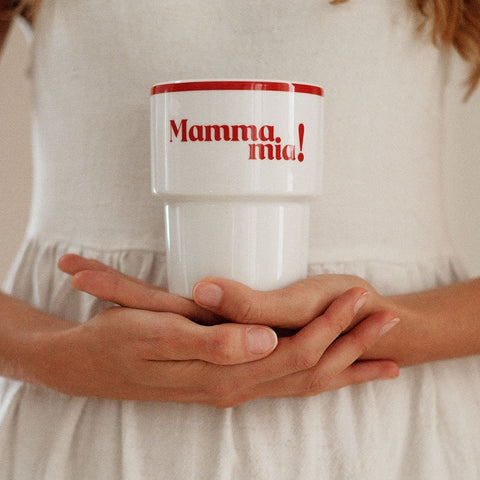 1. Woman holding Terra Mamma ceramic mug with 'Mamma Mia!' text in red, wearing white dress