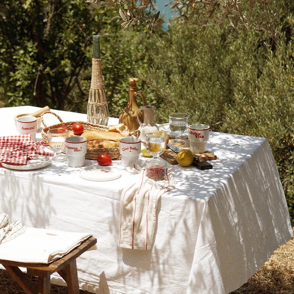5. Outdoor table setting with Terra Mamma ceramic mugs, bread, and tomatoes under olive trees