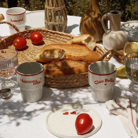 2. Terra Mamma ceramic mugs with 'Mamma Mia!' and 'Ciao Bella!' text on outdoor table with bread and tomatoes
