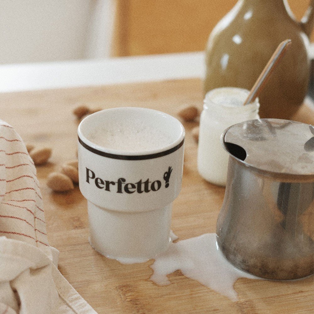 5. Terra Mamma Perfetto ceramic mug with 'Perfetto!' text on a wooden surface with spilled milk and a metal jug