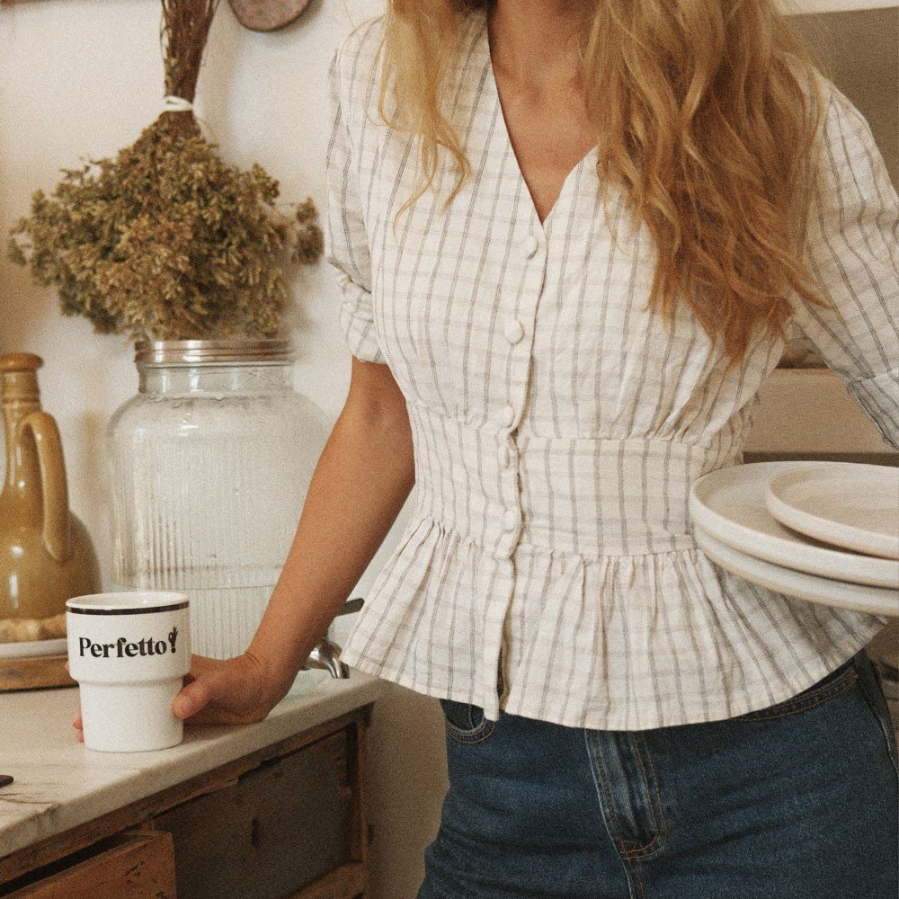3. Woman in a kitchen holding Terra Mamma Perfetto ceramic mug with 'Perfetto!' text, wearing a plaid blouse and jeans
