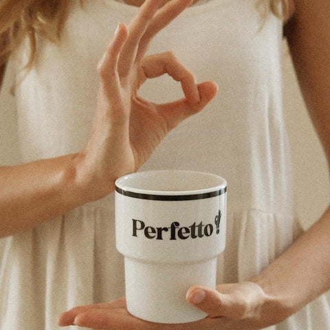 1. Woman holding Terra Mamma Perfetto ceramic mug with 'Perfetto!' text, making an okay gesture, wearing a white dress
