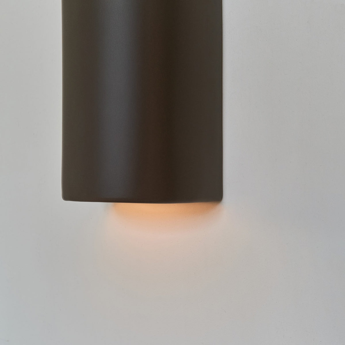 3. Close-up of brown ceramic wall light sconce by Ora showing warm light emission