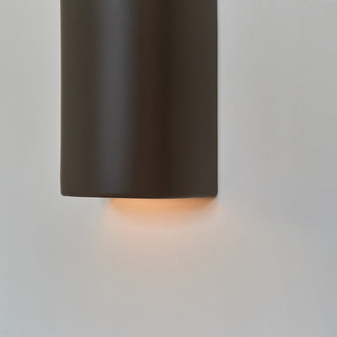 3. Close-up of brown ceramic wall light sconce by Ora showing warm light emission
