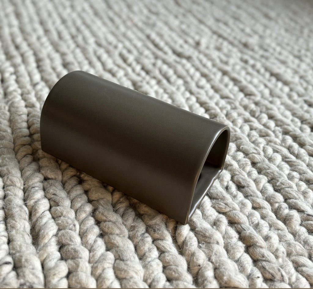 4. Brown ceramic wall light sconce by Ora on textured fabric surface