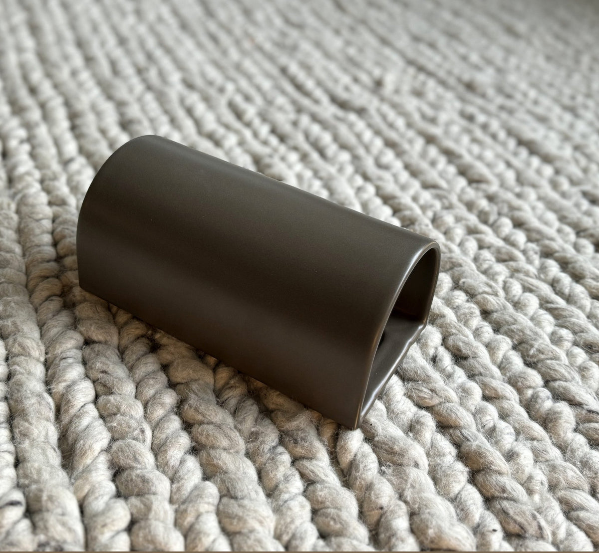 4. Brown ceramic wall light sconce by Ora on textured fabric surface