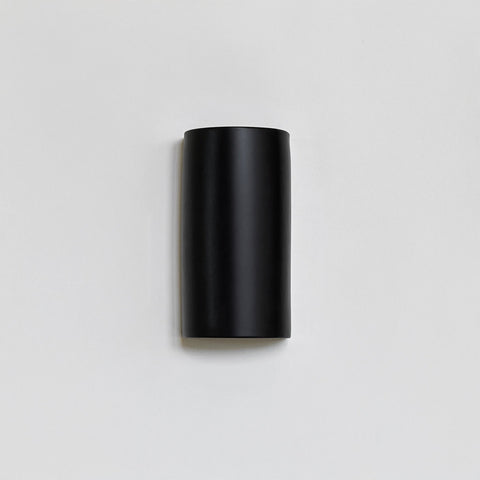 2. Black ceramic wall light by Ora on a plain background, unlit
