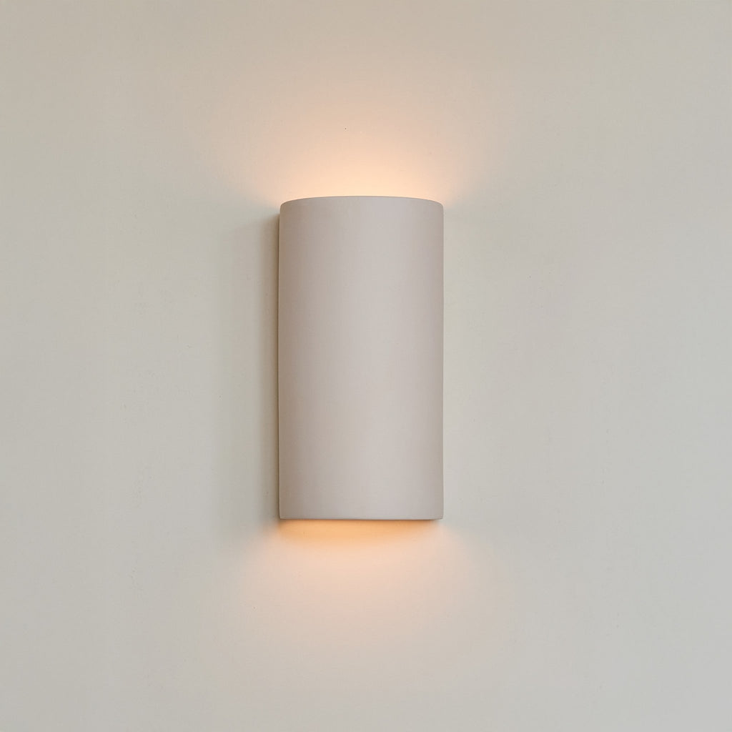 1. Ceramic wall light in extra matte white with warm glow on neutral wall