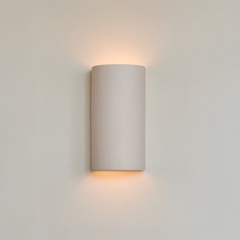 1. Ceramic wall light in extra matte white with warm glow on neutral wall