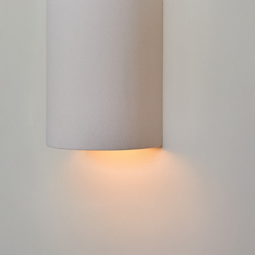 2. Close-up of extra matte white textured ceramic wall light by Ora, highlighting the warm glow from the bottom.