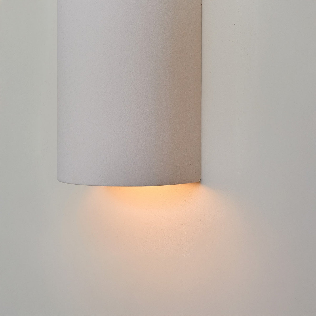 2. Close-up of extra matte white textured ceramic wall light by Ora, highlighting the warm glow from the bottom.